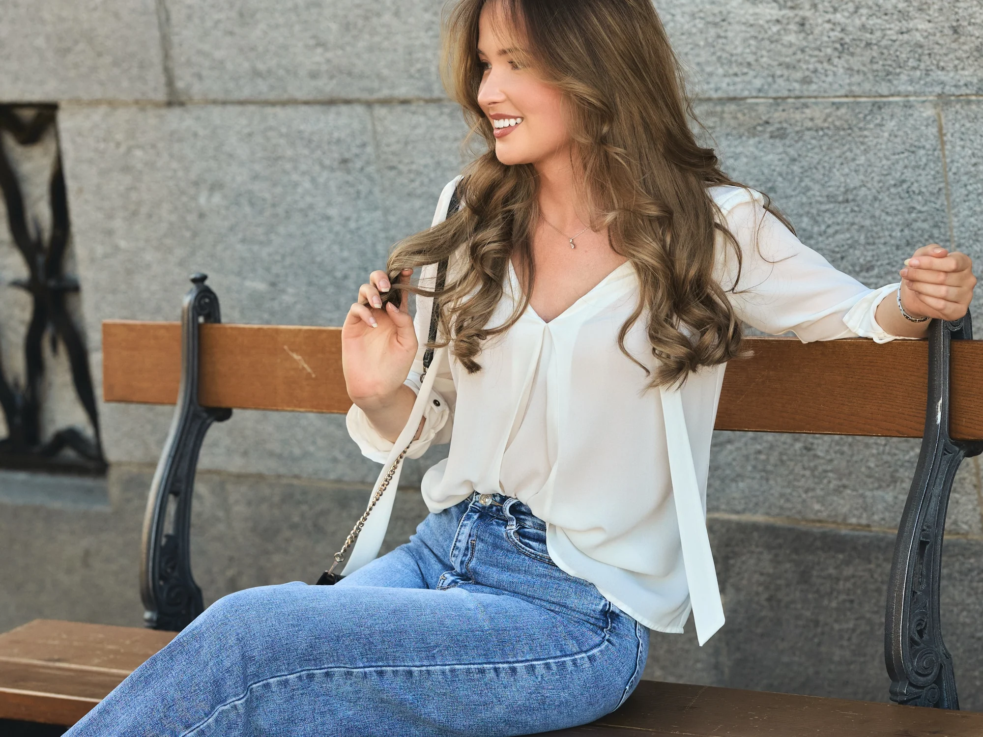 Eloïse, modèle, assise sur un banc en pierre, sourire et regard de côté, Bâle