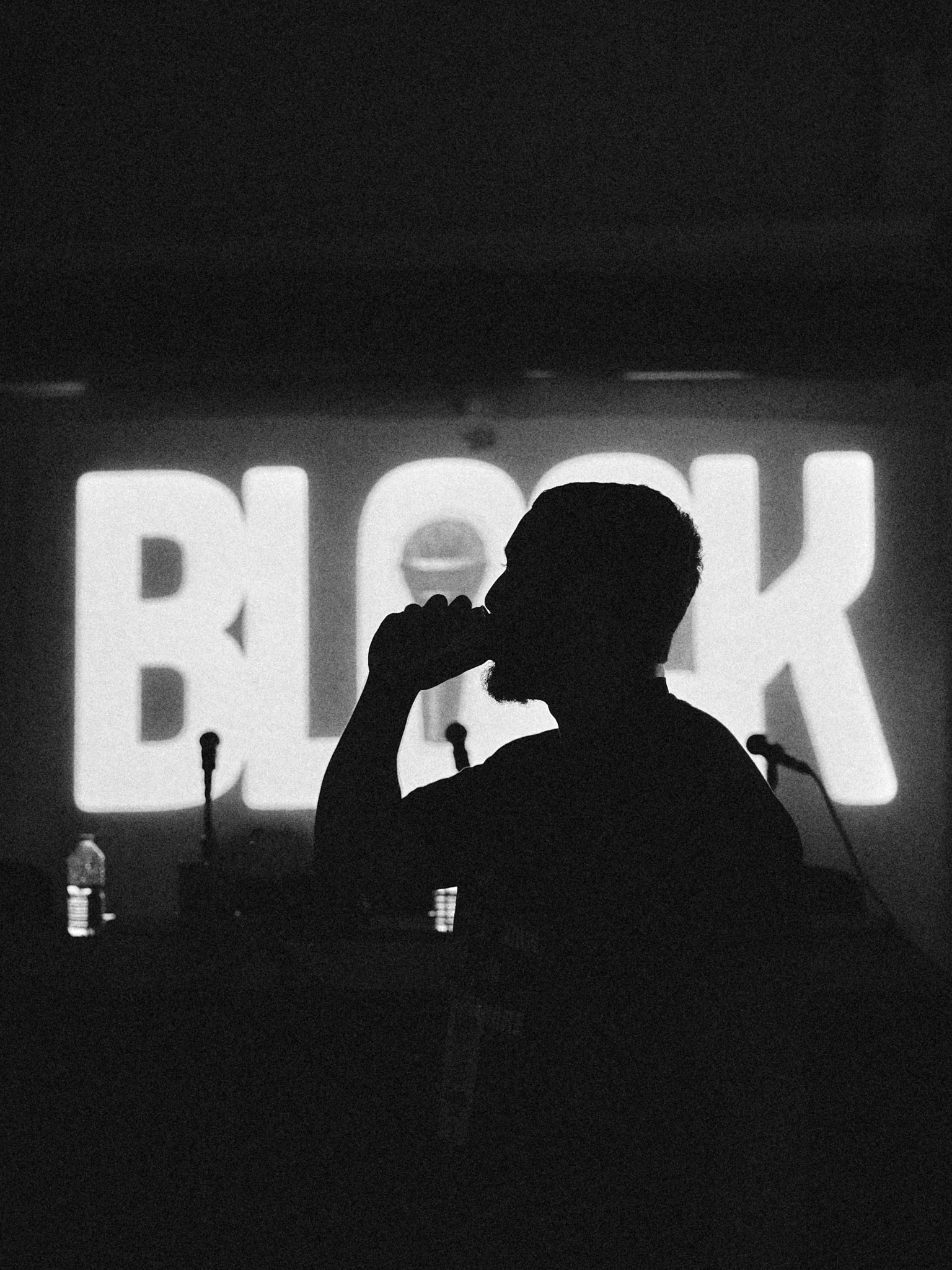 Silhouette d'un rappeur qui boit, devant le logo Block projeté, battle de freestyle à Mulhouse