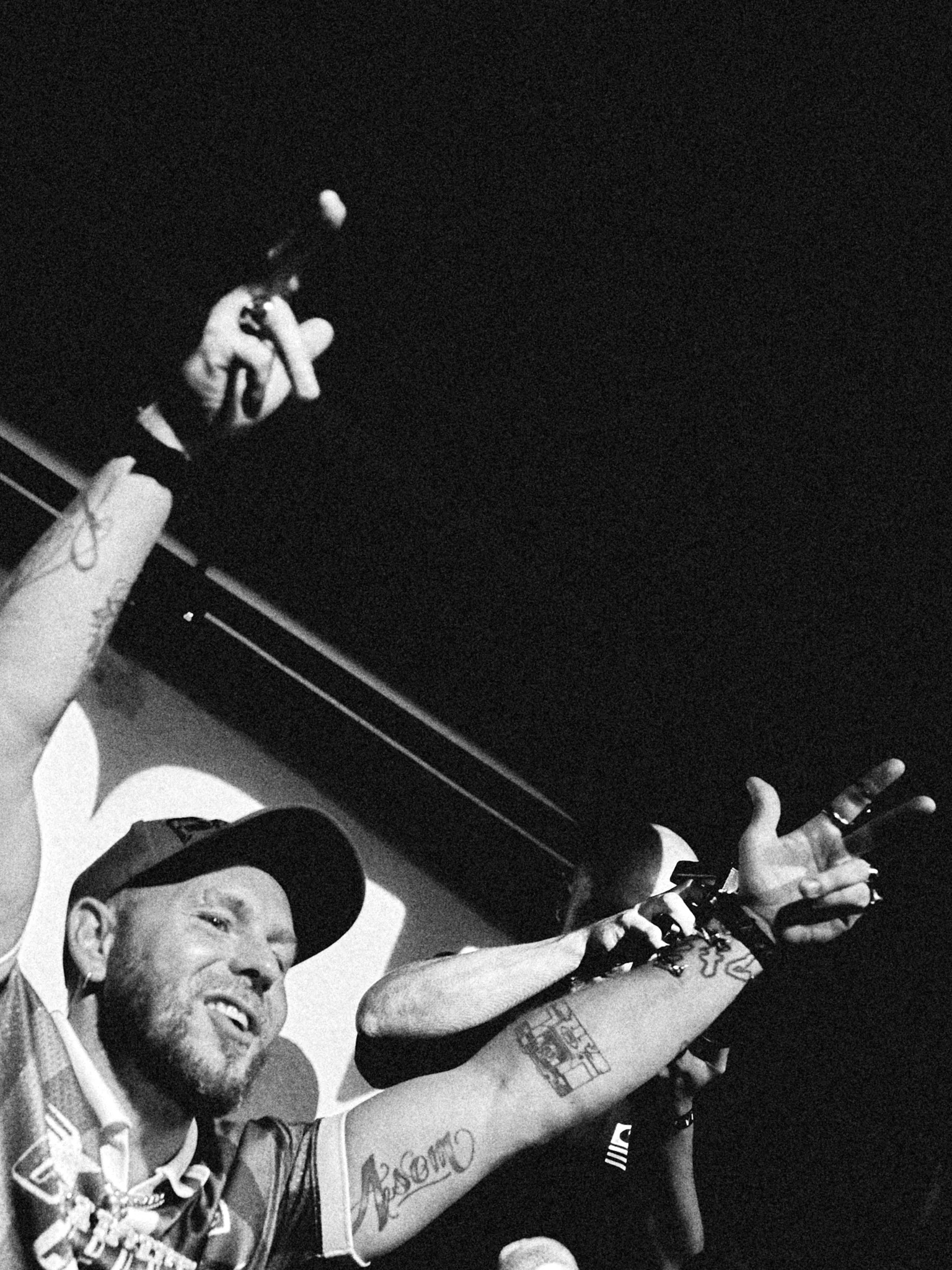 Rappeur souriant, bras tendus vers le public pendant la battle, noir et blanc
