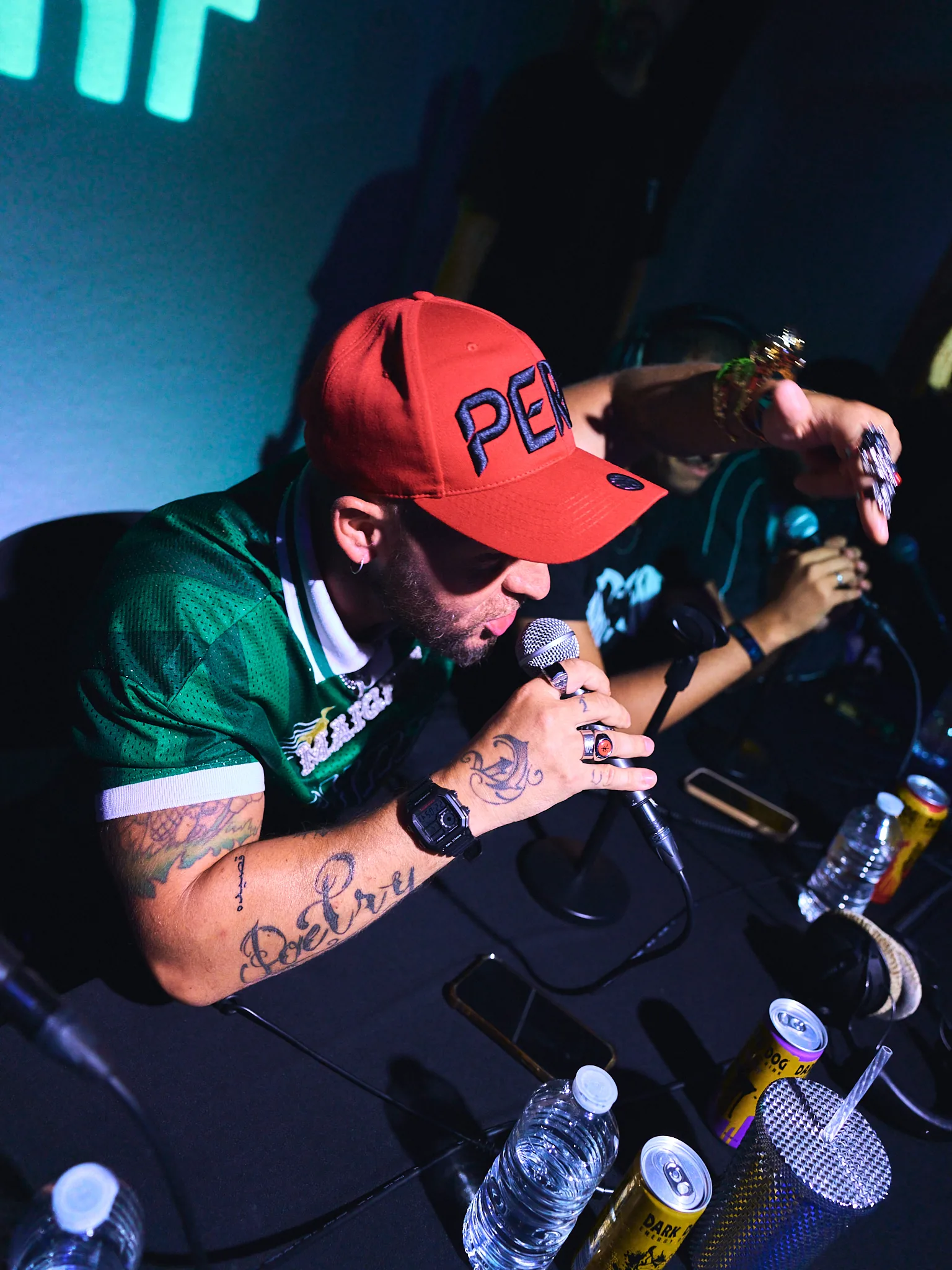 Rappeur en casquette rouge et maillot vert penché sur son micro, battle de freestyle, Mulhouse